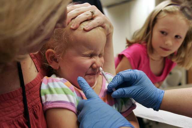 A girl receives the H1N1 nasal mist vaccine at Wake County Human Services in Raleigh, North Carolina, U.S., on Friday, Oct. 9, 2009. A group of New York doctors and health-care workers who are to be among the first inoculated against swine flu asked a federal judge to void U.S. approval of the vaccine until more safety tests are done. Photographer: Jim R. Bounds/Bloomberg